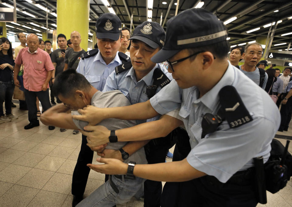 Police restrain an angry passenger who tried to fight with protesters in Hong Kong on Tuesday, July 30, 2019. Protesters in Hong Kong have disrupted subway service during the morning commute by blocking the doors on trains, preventing them from leaving the stations. (AP Photo/Vincent Yu)