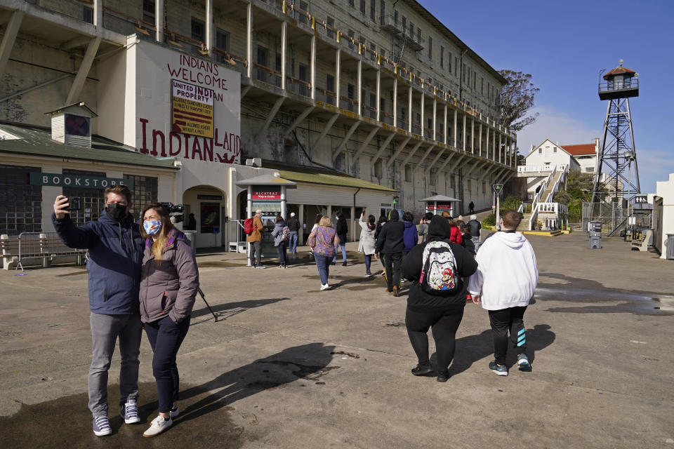 A couple takes a selfie as visitors return to Alcatraz Island in San Francisco, Monday, March 15, 2021. The historic island prison was reopened to visitors Monday after being closed since December because of the coronavirus threat. Visitors were also able to tour the inside of the main cell house for the first time in a year. (AP Photo/Eric Risberg)