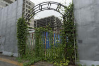 An entrance covered with overgrown plants is seen near an abandoned construction project on the outskirts of Beijing, Thursday, July 25, 2024. (AP Photo/Ng Han Guan)