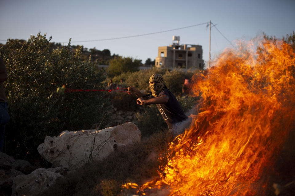 A Palestinian protester uses slingshot to hurls stones during protest against the West Bank Jewish settlement outpost of Eviatar that was rapidly established last month, at the Palestinian village of Beita, near the West Bank city of Nablus, Thursday, June 24, 2021. The Palestinians say it was established on their farmland and fear it will grow and merge with other large settlements in the area. (AP Photo/Majdi Mohammed)