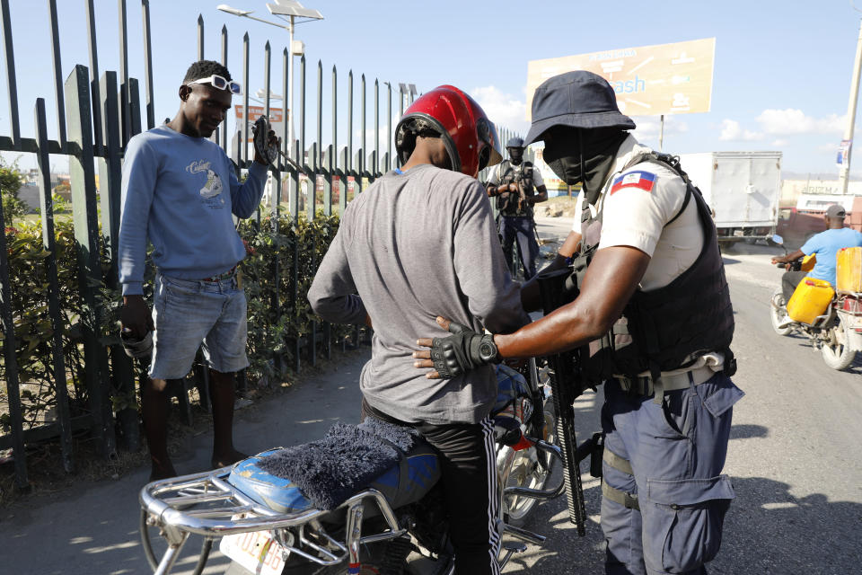 Un policía registra a un motorista en un puesto de control en Puerto Príncipe, Haití, el 26 de enero de 2024. (AP Foto/Odelyn Joseph)