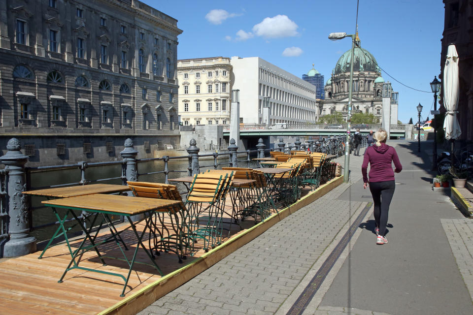 06 May 2020, Berlin: A woman walks past empty tables and chairs of a closed restaurant in the Nikolai quarter. In the background you can see the Berlin Cathedral and the Humboldt-Forum. The Federal Government and the heads of the federal states are discussing the reopening of restaurants and pubs from 09.05.2020. Photo: Wolfgang Kumm/dpa (Photo by Wolfgang Kumm/picture alliance via Getty Images)