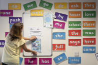 Reception teacher Elizabeth Dockry places signage in a classroom as measures are taken to prevent the transmission of coronavirus before the possible reopening of Lostock Hall Primary school in Poynton near Manchester, England, Wednesday May 20, 2020. Since March 20, the coronavirus has forced British schools to close to all but a small number of key workers' children and those under social care. The government wants children to start returning to primary schools in stages from June 1. Those going back first include the youngest — ages 4 to 6. (AP Photo/Jon Super)