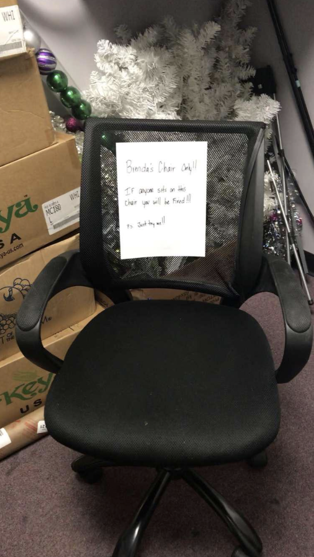 A picture of the chair in question with a sign on it that says "Brenda's chair only, if anyone sits on this, you'll be fired, P.S. just try me"