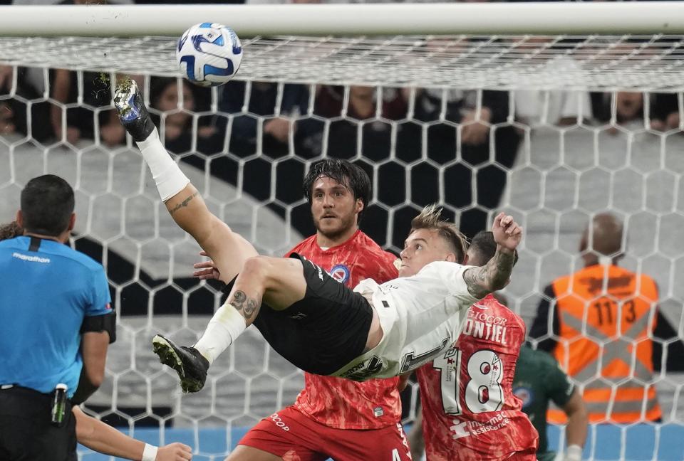 Roger Guedes, de Corinthians de Brasil, anota con una chilena frente a Kevin Mac Allister y Santiago Montiel, de Argentinos Juniors, durante un partido de la Copa Libertadores, disputado en Sao Paulo el 19 de abril de 2023 (AP Foto/Andre Penner)