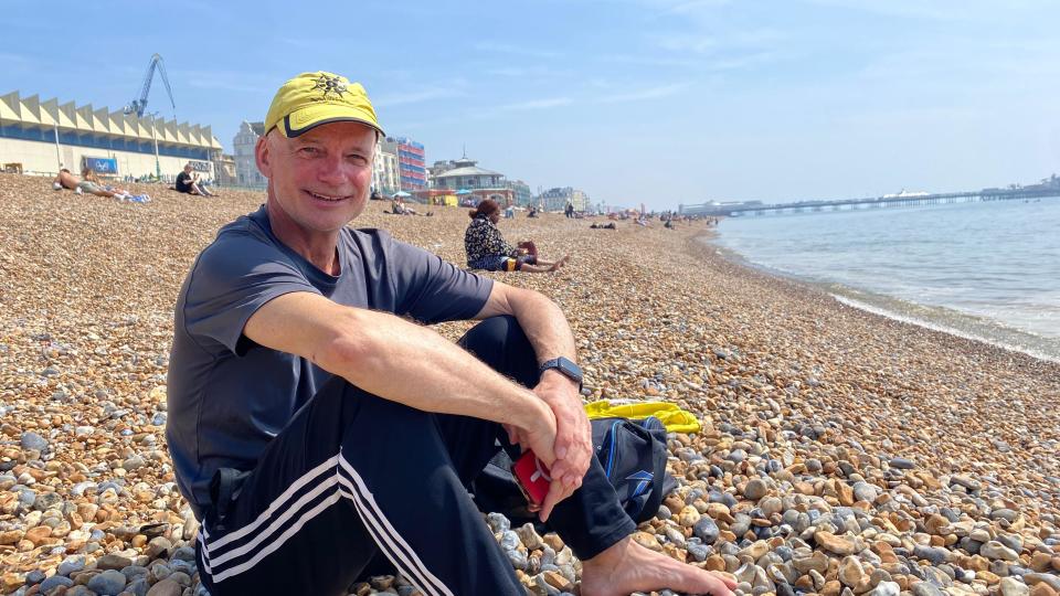 a man in a yellow cap and grey t-shirt sat on Brighton beach