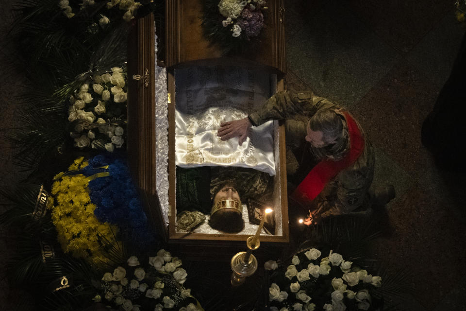 A Ukrainian army chaplain pays his respects at the coffin of Ukrainian serviceman and famous Ukrainian poet Maksym Kryvtsov, who was killed in a battle with the Russian troops, during the funeral ceremony in St. Michael Cathedral in Kyiv, Ukraine, Thursday, Jan. 11, 2024. (AP Photo/Efrem Lukatsky)