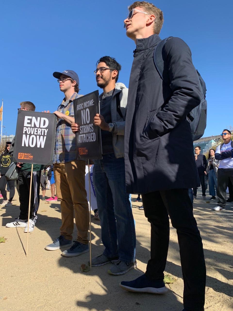 Victor Garcia, center, holds up a sign at a rally organized by Democratic presidential candidate Andrew Yang in downtown San Francisco. Garcia says he likes a lot about Yang's positions, but is still waiting for candidates to speak more directly to issues that Latinos in the state care about.