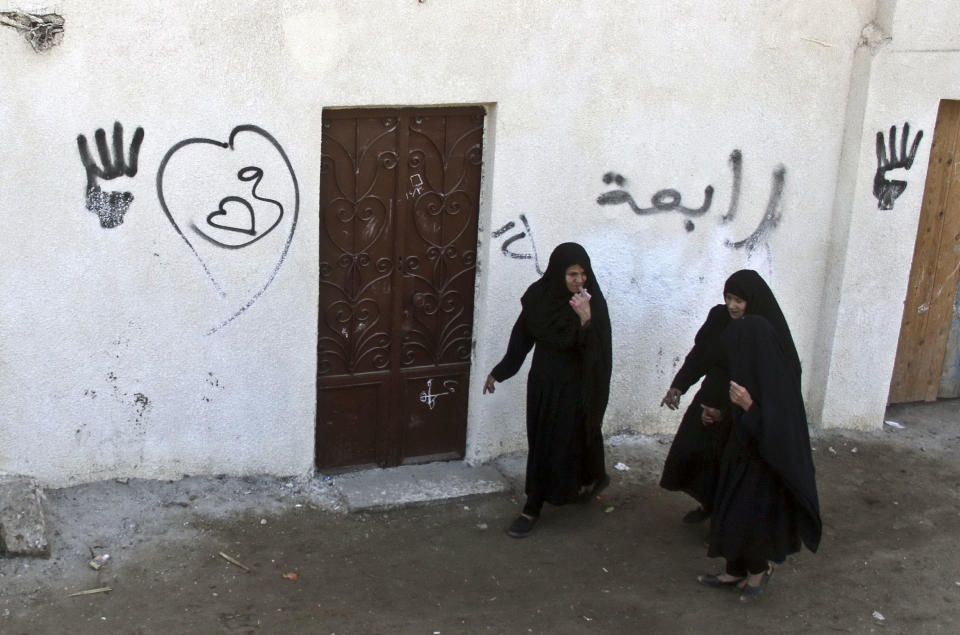 Egyptian women walk near a polling station during the country's constitutional referendum in Dalga, Minya province, Egypt, Tuesday, Jan. 14, 2014. Egyptians are voting Tuesday on a draft for their country's new constitution that represents a key milestone in a military-backed roadmap put in place after President Mohammed Morsi was overthrown in a popularly backed coup last July. Arabic on the wall reads, "Rabaa." (AP Photo/Roger Anis, El Shorouk) EGYPT OUT