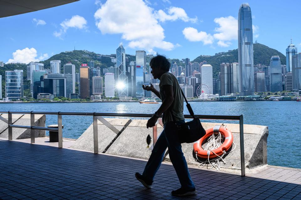 An angler carries a fish on a hook as he walks along a promenade on the Kowloon side of Victoria Harbour, which faces the skyline of Hong Kong Island, in Hong Kong on July 13, 2020. (Photo by Anthony WALLACE / AFP) (Photo by ANTHONY WALLACE/AFP via Getty Images)
