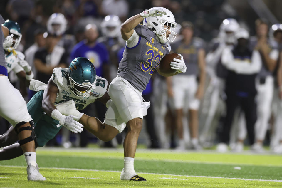 San Jose State running back Kairee Robinson (32) gets away from Coastal Carolina safety Clayton Isbell (22) during the first half of the Hawaii Bowl NCAA college football game Saturday, Dec. 23, 2023, in Honolulu. (AP Photo/Marco Garcia)