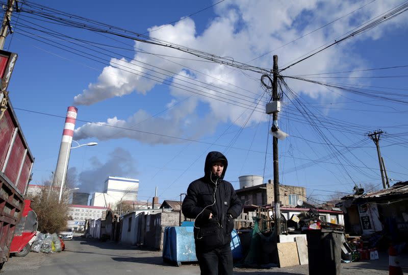 FILE PHOTO: A man walks near a coal-fired power plant in Harbin