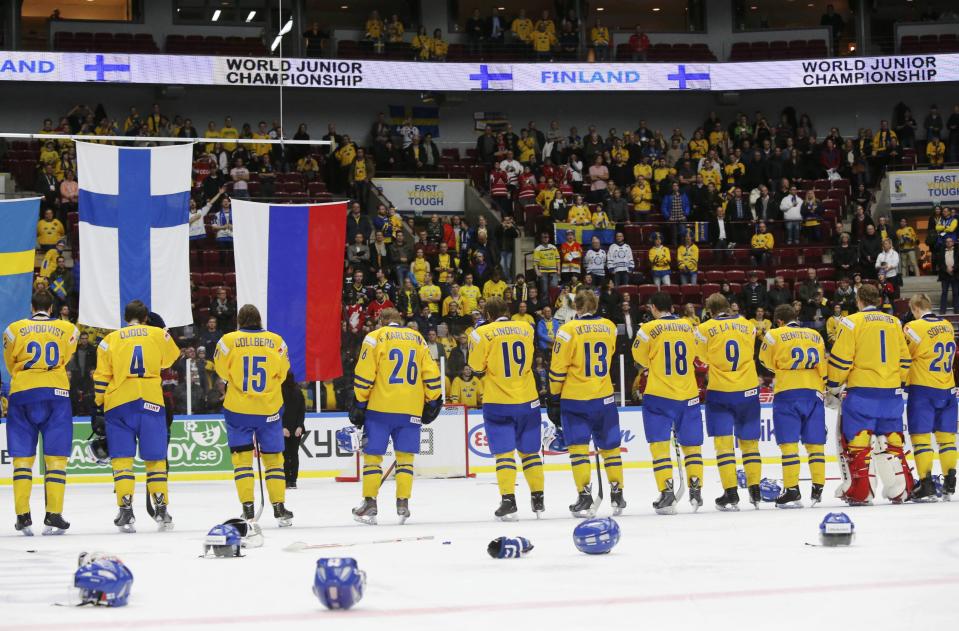 Sweden's team watch the flag of Finland being raised for the after losing in overtime of their IIHF World Junior Championship gold medal ice hockey game in Malmo, Sweden, January 5, 2014. REUTERS/Alexander Demianchuk (SWEDEN - Tags: SPORT ICE HOCKEY)