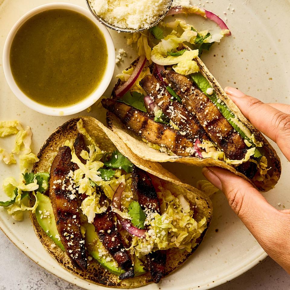 grilled portobello tacos topped with cabbage slaw, avocado, and queso fresco beside a bowl of salsa verde