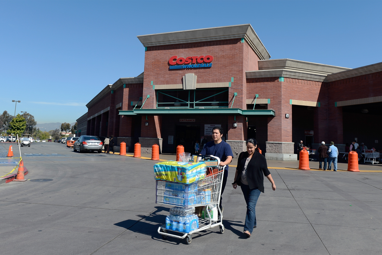 Two people walking outside of Costco with their shopping cart