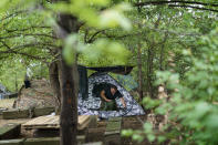 A member of the Dnipro-1 regiment cleans his tent during a period of relative calm around their position near Sloviansk, Donetsk region, eastern Ukraine, Friday, Aug. 5, 2022. While the lull in rocket strikes has offered a reprieve to remaining residents, some members of the Ukrainian military unit say it could be a prelude to renewed attacks. (AP Photo/David Goldman)