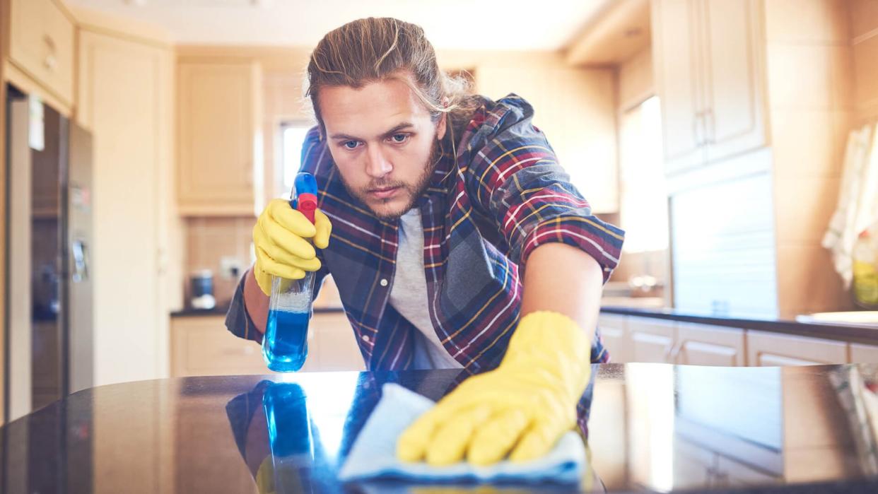 Shot of a young man cleaning his home.