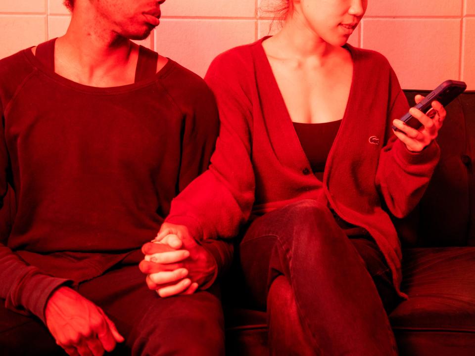 couple holding hands while woman looking at phone