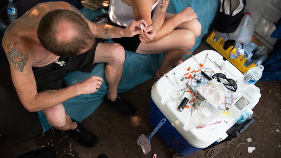 Kerri and Josh, a couple from Williamstown, share a cigarette at their homeless encampment site in Camden on July 18, 2023.