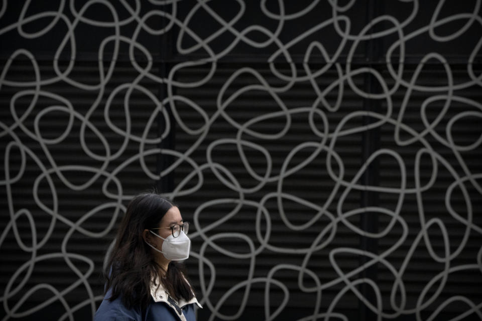 A woman wearing a face mask walks at a shopping and office complex in Beijing, Wednesday, Jan. 11, 2023. Japan and South Korea on Wednesday defended their border restrictions on travelers from China, with Tokyo criticizing China's move to suspend issuing new visas in both countries as a step unrelated to virus measures. (AP Photo/Mark Schiefelbein)