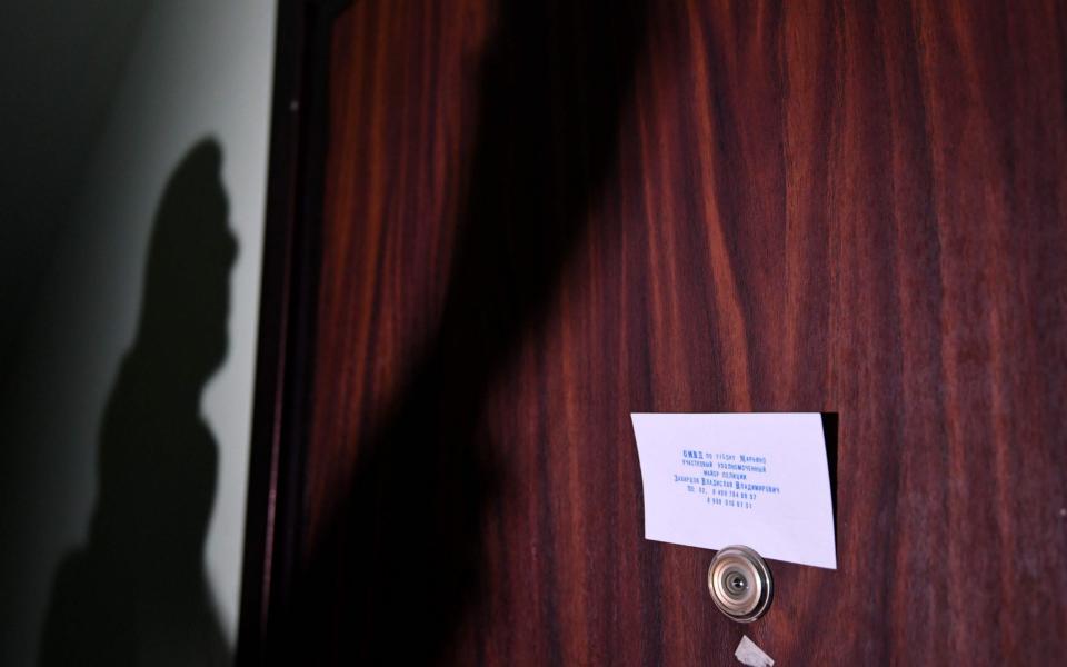 A card with contacts of a local police chief fixed to the door of the flat of Mr Navalny - NATALIA KOLESNIKOVA /AFP