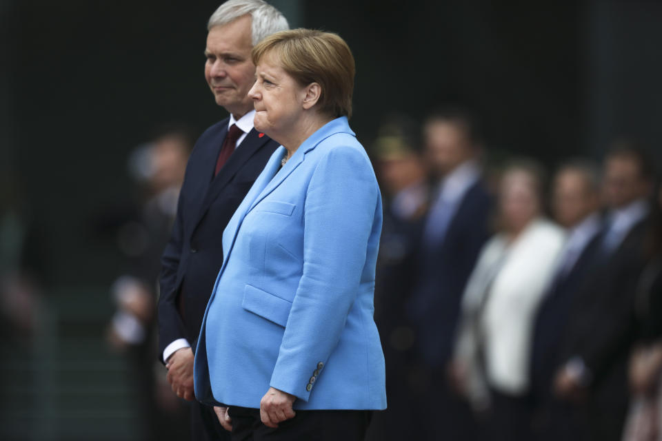 German Chancellor Angela Merkel, right, and Prime Minister of Finland Antti Rinne listen to the national anthems at the chancellery in Berlin, Germany, Wednesday, July 10, 2019. Merkel's body shook visibly as she stood alongside the Finnish prime minister and listen to the national anthems during the welcoming ceremony at the chancellery.(AP Photo/Markus Schreiber)