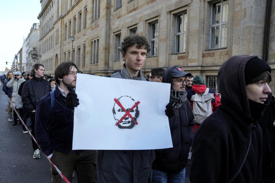 A man shows a protest placard as he queues with other voters near the polling station at the Russian embassy in Berlin, after noon local time, on Sunday, March 17, 2024. The Russian opposition has called on people to head to polling stations at noon on Sunday in protest as voting takes place on the last day of a presidential election that is all but certain to extend President Vladimir Putin's rule after he clamped down on dissent. AP can't confirm that all the voters seen at the polling station at noon were taking part in the opposition protest. (AP Photo/Ebrahim Noroozi)