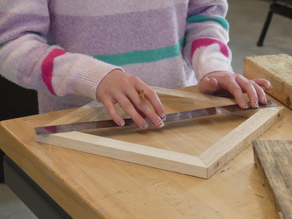 Taylor Pelletier, an eighth grader at Edgewood Junior High School, marks measurements on a wooden frame Nov. 18 in the school's design lab.