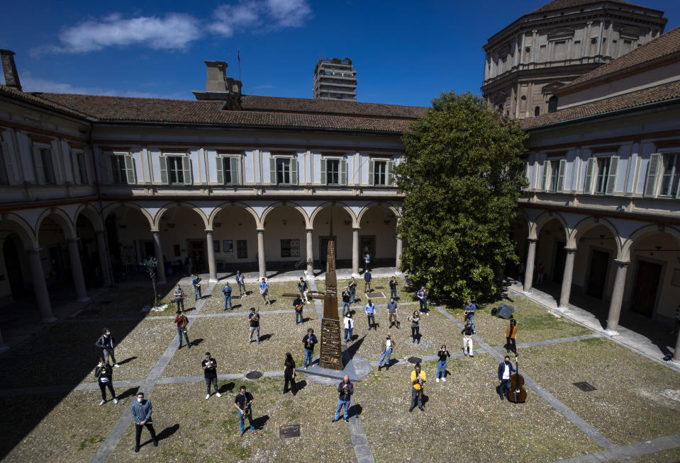 Jazz orchestra musicians and singers wear face masks to curb the spread of COVID-19 as they gather at the Giuseppe Verdi Music Conservatory's cloister before playing a rehearsal, in Milan, Italy, Friday, May 7, 2021. Whatever the instrument, flute, violin or drums, students at Italy's oldest and largest music conservatory have been playing behind plexiglass screens during much of the pandemic as the Conservatory found ways to preserve instruction throughout Italy’s many rolling lockdowns. (AP Photo/Antonio Calanni)