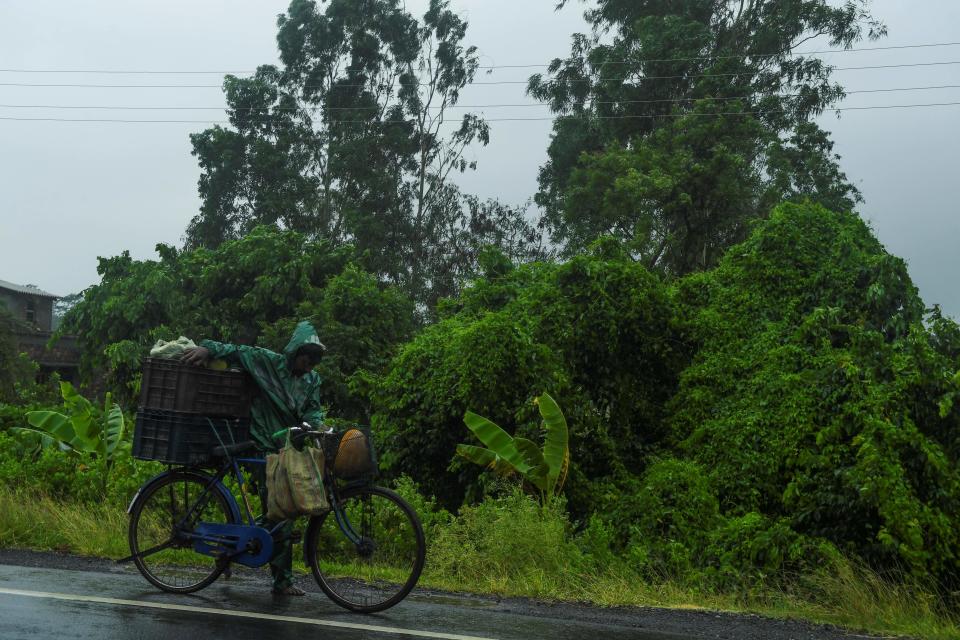 A man pushes a bicycle loaded with vegetable under the rain ahead of the expected landfall of cyclone Amphan in Midnapore, West Bengal, on May 20, 2020. (Photo by DIBYANGSHU SARKAR/AFP via Getty Images)