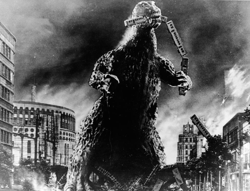 Radioactive monster Godzilla stomps through a city and eats a commuter train in a scene from 'Godzilla, King of the Monsters!,' directed by Ishiro Honda and Terry O. Morse, 1956. The film is actually a reedited version of the 1954 film 'Gojira,' directed by Honda, with several new scenes added which were directed by Morse. (Photo by Embassy Pictures/Courtesy of Getty Images)