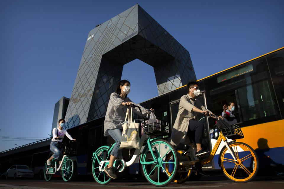 People wear face masks to protect against the new coronavirus as they ride bicycles in the central business district in Beijing, Tuesday, May 26, 2020. With declining virus case numbers, students have gradually returned to class and some international schools in Beijing are preparing to reopen on June 1. China's ceremonial parliament is meeting this week, with social distancing and other anti-virus measures being used. (AP Photo/Mark Schiefelbein)