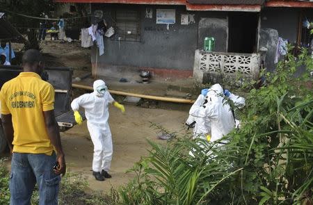 Medical staff wearing protective suits gather at a health facility near the Liberia-Sierra Leone border in western Liberia November 5, 2014. REUTERS/James Giahyue