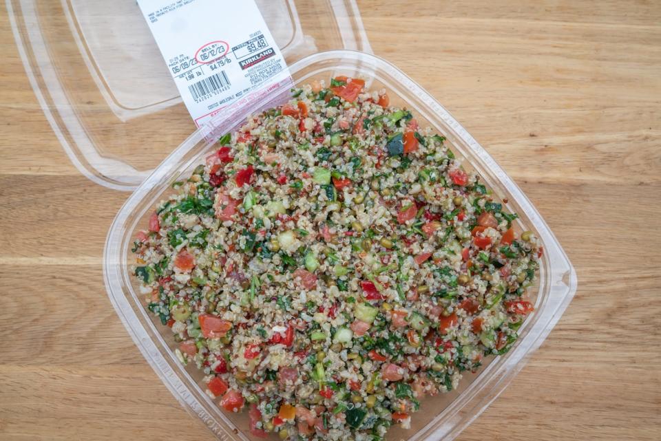 quinoa salad with chopped produce in open plastic container on wood