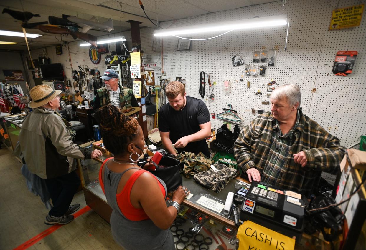 Tim Carpenter, right, owner of the Foxhole PX Store in Lansing, and son Tyler, middle, cash out customers Tuesday, May 7, 2024, at the store. Tim and his wife Kelly plan to "spend time with the grandkids and travel" upon retirement. The store will close permanently Saturday.