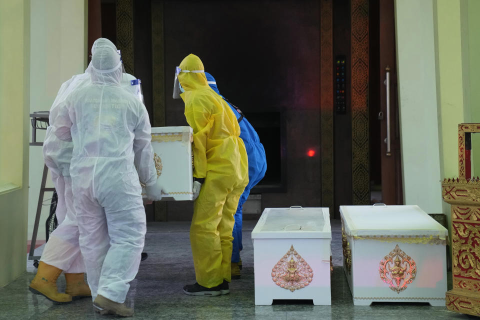 Siam Nonthaburi Foundation volunteers in full protective suits carry a coffin containing a COVID-19 victim to a cremation rite for free funeral ceremony service at Wat Ratprakongtham temple Nonthaburi Province, Thailand, Monday, July 12, 2021. Wat Ratprakongtham temple offering free funeral service for people dying from COVID-19 says it is struggling to keep up with 24-hour cremation, and is adding another crematorium as Thailand sees a growing number of cases and deaths in a coronavirus surge that began in early April. (AP Photo/Sakchai Lalit)