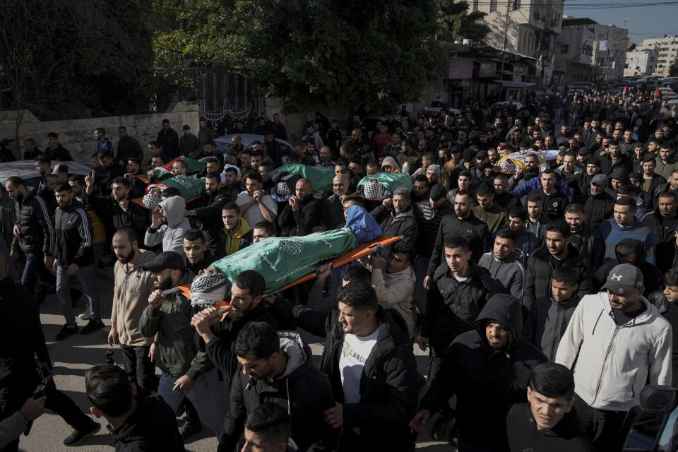 Mourners carry the bodies of six Palestinians draped in the Hamas flags during their funeral in the West Bank city of Jenin on Sunday, Jan. 7, 2024. Six Palestinians and a member of Israel's paramilitary border police were killed in confrontations in a hot spot of violence in the Israeli-occupied West Bank, the Palestinian Health Ministry and the Israeli military said Sunday. (AP Photo/Majdi Mohammed)