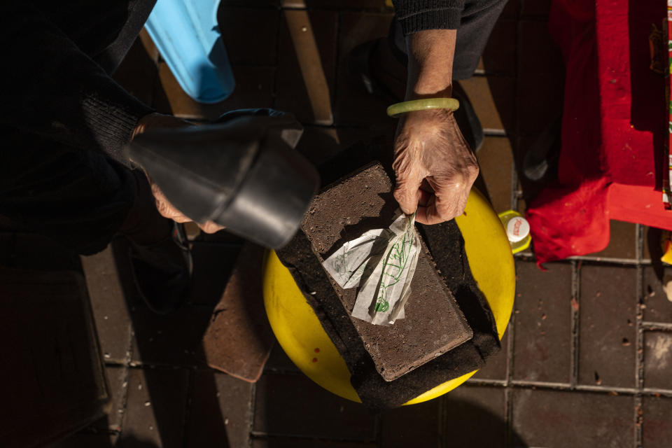 A practitioner performs a "villain hitting" ceremony under the Canal Road Flyover in Hong Kong, on Sunday, March 5, 2023. People holding a grudge may have found a way to release it in Hong Kong’s “villain hitting” ritual. To relieve themselves from a bad mood, customers paid ritual practitioners who work underneath the Canal Road Flyover in Causeway Bay, one of the city's shopping districts, and watched them bashing an image of their target with a shoe. It could be anyone — rival lovers and unfriendly colleagues, or horrible bosses and unlikeable public figures. (AP Photo/Louise Delmotte)