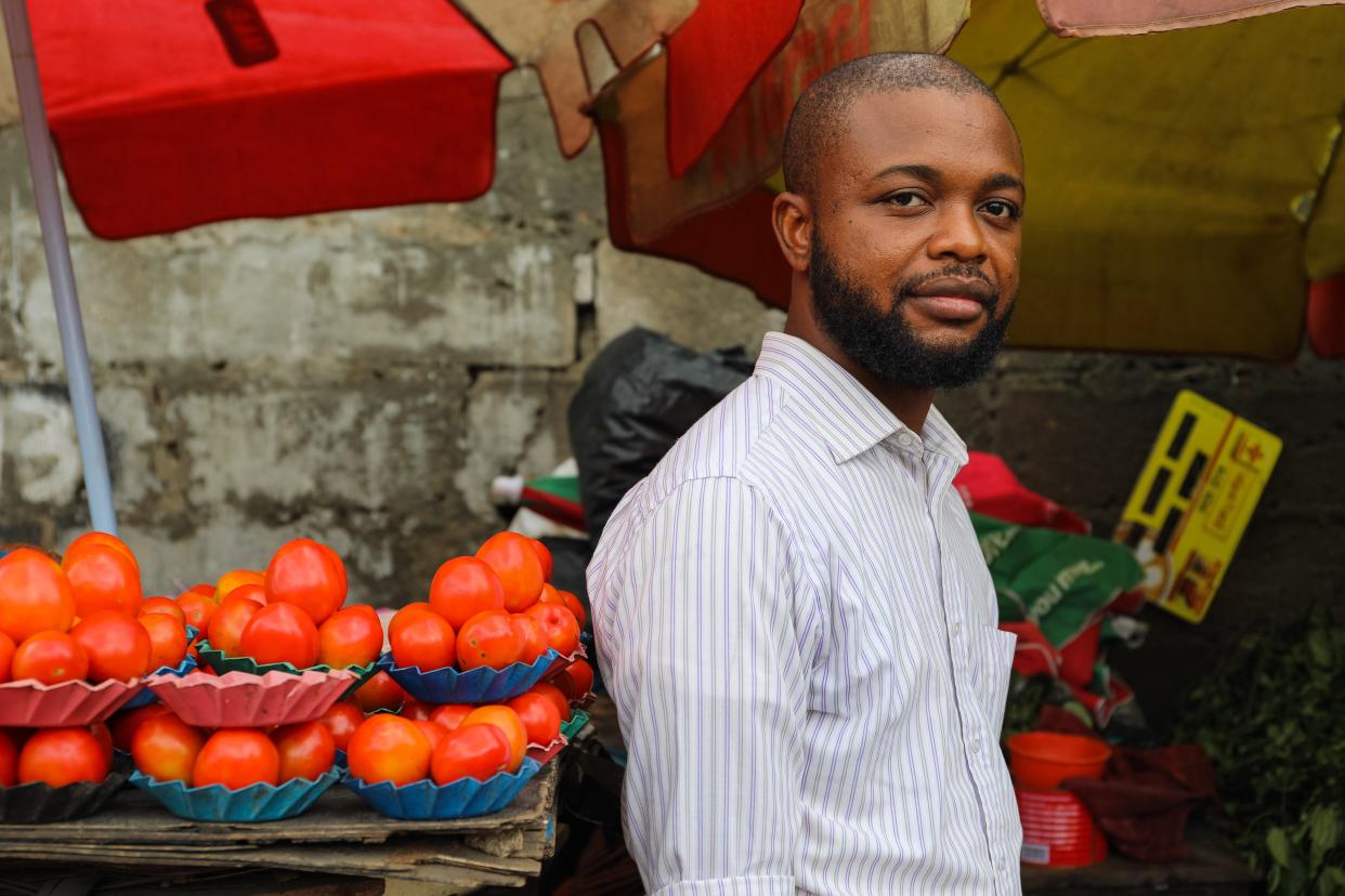 Adeniyi Shoremi by a stack of tomatoes at a local market in Lagos.