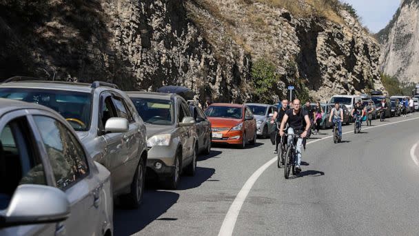 PHOTO: People ride bicycles along a queue of vehicles at the Verkhny Lars checkpoint in North Ossetia, Russia on the border to Georgia, on Sept. 27, 2022. Around 3.5 thousand cars are queueing at the checkpoint to cross the border from Russia to Georgia. (Yelena Afonina/TASS via ZUMA Press)