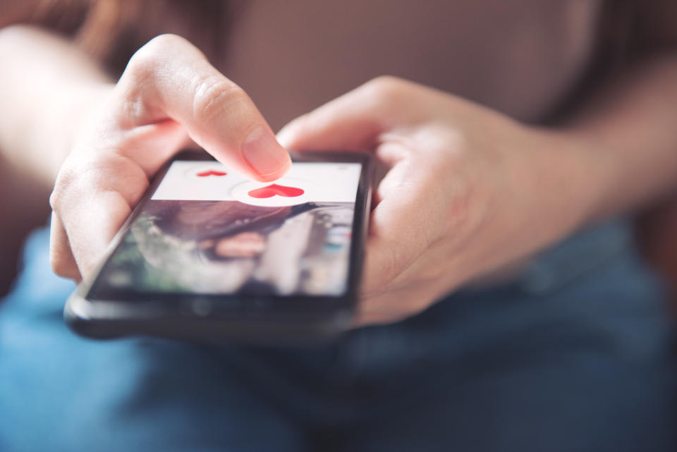 Finger of woman pushing heart icon on screen in mobile smartphone application. Online dating app, valentine's day concept.