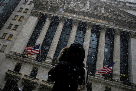 A woman stops to photograph the New York Stock Exchange, (NYSE) as snow begins to fall during the morning commute in New York City, U.S., February 7, 2018. REUTERS/Brendan McDermid