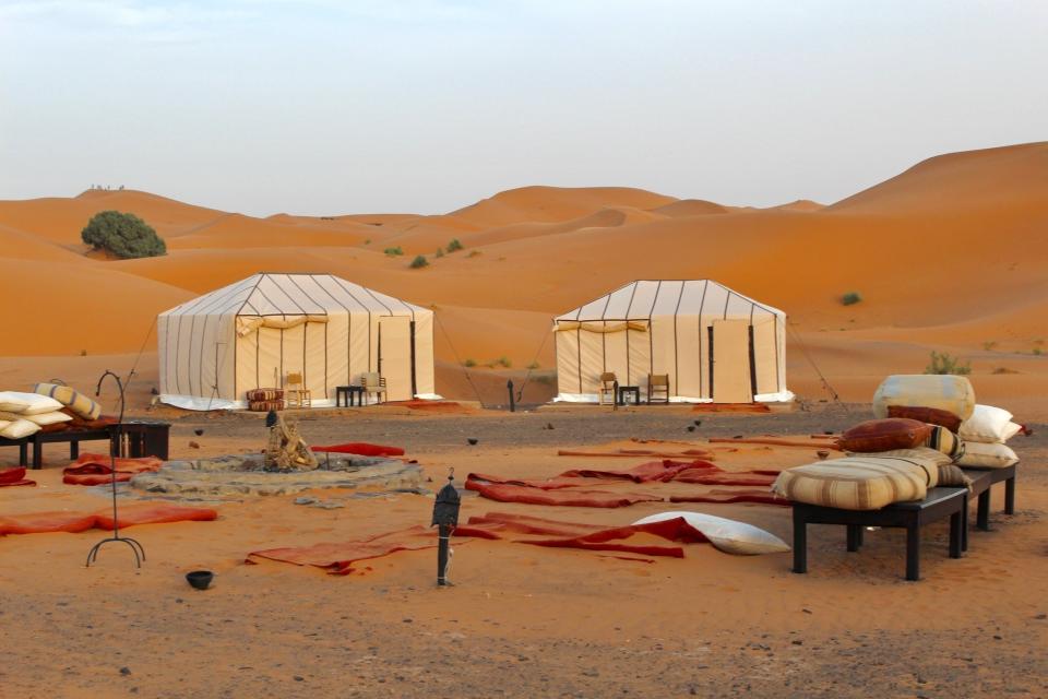 A campsite and tents surrounded by dunes in the Sahara Desert.