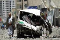 A Yemeni walks past a vehicle which was damaged the day before during an air strike by Saudi-led coalition warplanes on the nearby base on Fajj Attan hill in the capital Sanaa on April 21, 2015