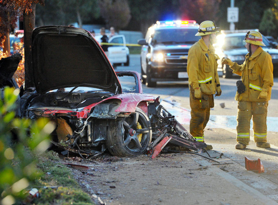 FILE - In this Saturday, Nov. 30, 2013, file photo, firefighters work next to the wreckage of a Porsche that crashed into a light pole killing actor Paul Walker and his Roger Rodas in Valencia, Calif. Crash investigators have determined that the Porsche was traveling approximately 90 mph when it lost control on a city street and smashed into a light pole, killing the actor and his friend. A person who has reviewed the investigators’ report told The Associated Press that it concluded unsafe driving, not mechanical problems, caused the crash. The person requested anonymity because the report has not been officially released yet. (AP Photo/The Santa Clarita Valley Signal, Dan Watson) LOS ANGELES DAILY NEWS OUT. MANDATORY CREDIT