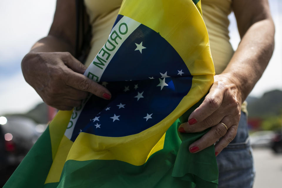 A former supporter of Brazil's President Jair Bolsonaro holds a Brazilian flag during a protest against the government's response in combating COVID-19 and demanding his impeachment, in Rio de Janeiro, Brazil, Sunday, Jan. 24, 2021. (AP Photo/Bruna Prado)