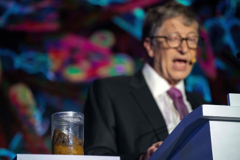 Microsoft founder Bill Gates (R) talks next to a container (L) with human feces during the 