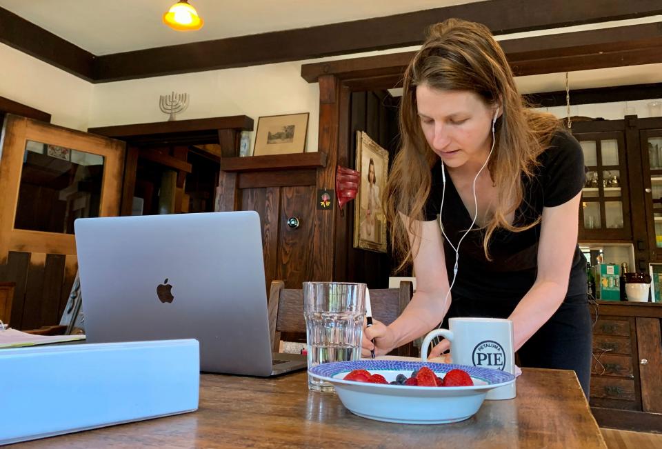 Martha Lackritz-Peltier, attorney at TechSoup, talks to one of her colleagues over the phone while working from her living room in Oakland, California, March 12, 2020. - Martha Lackritz-Peltier, an attorney at nonprofit group TechSoup, is working from her home in Oakland, where her companions include two dogs and hummingbirds flitting about the garden. (Photo by Julie JAMMOT / AFP) (Photo by JULIE JAMMOT/AFP via Getty Images)