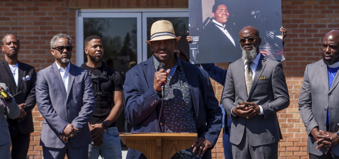 Herman Whitfield Jr., father of Herman Whitfield III (pictured on poster), speaks alongside members of faith in Indiana, Concerned Clergy of Indianapolis, and other community members, Tuesday, April 11, 2023, in Indianapolis. (Mykal McEldowney/The Indianapolis Star via AP)