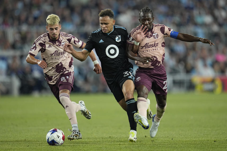 Minnesota United midfielder Hassani Dotson, center, battles for possession against Portland Timbers forward Diego Gutierrez, left, and midfielder Diego Chará, right, during the second half of an MLS soccer match, Saturday, July 1, 2023, in St. Paul, Minn. (AP Photo/Abbie Parr)